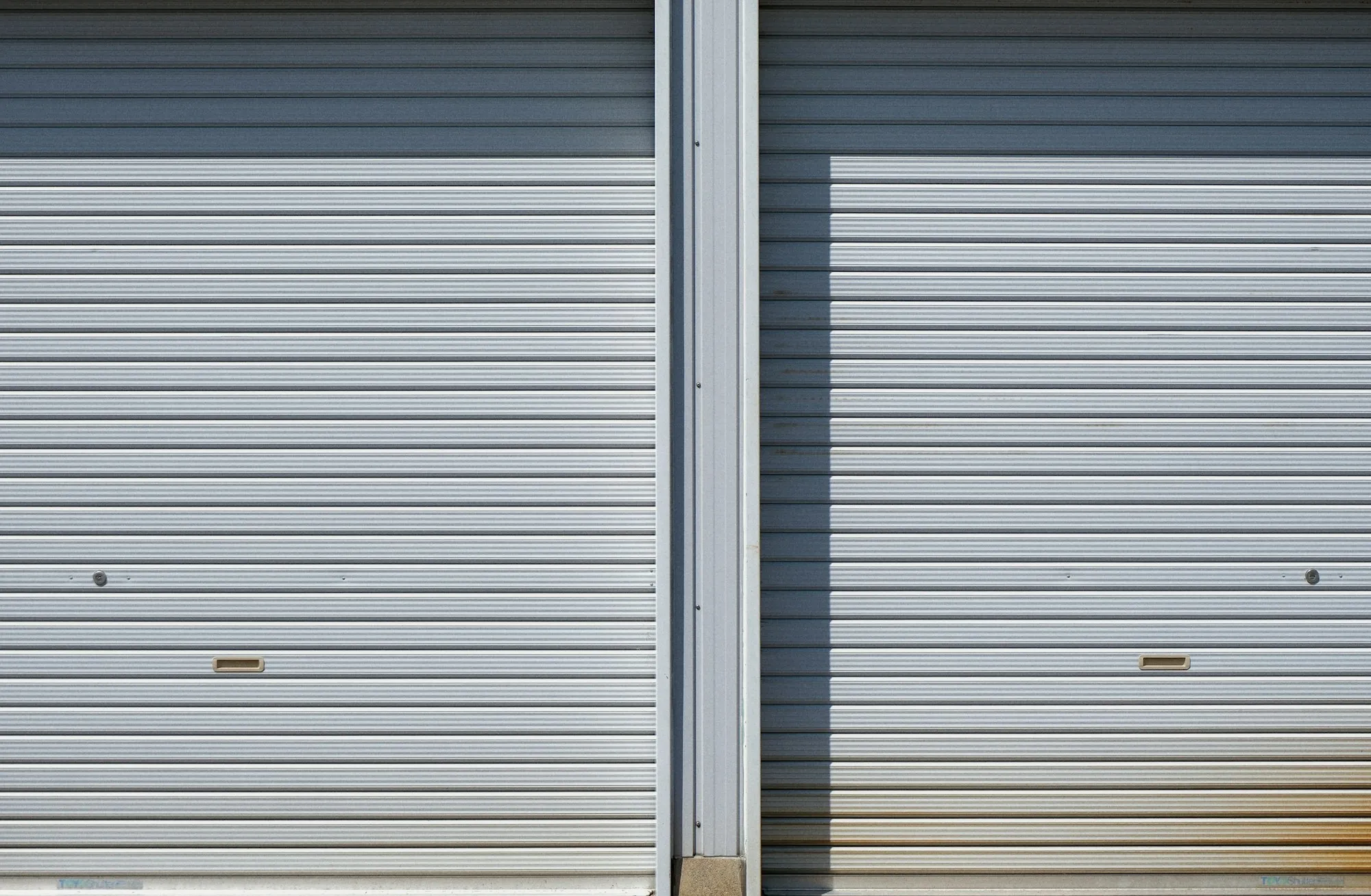 Two closed metal roll-up doors side by side